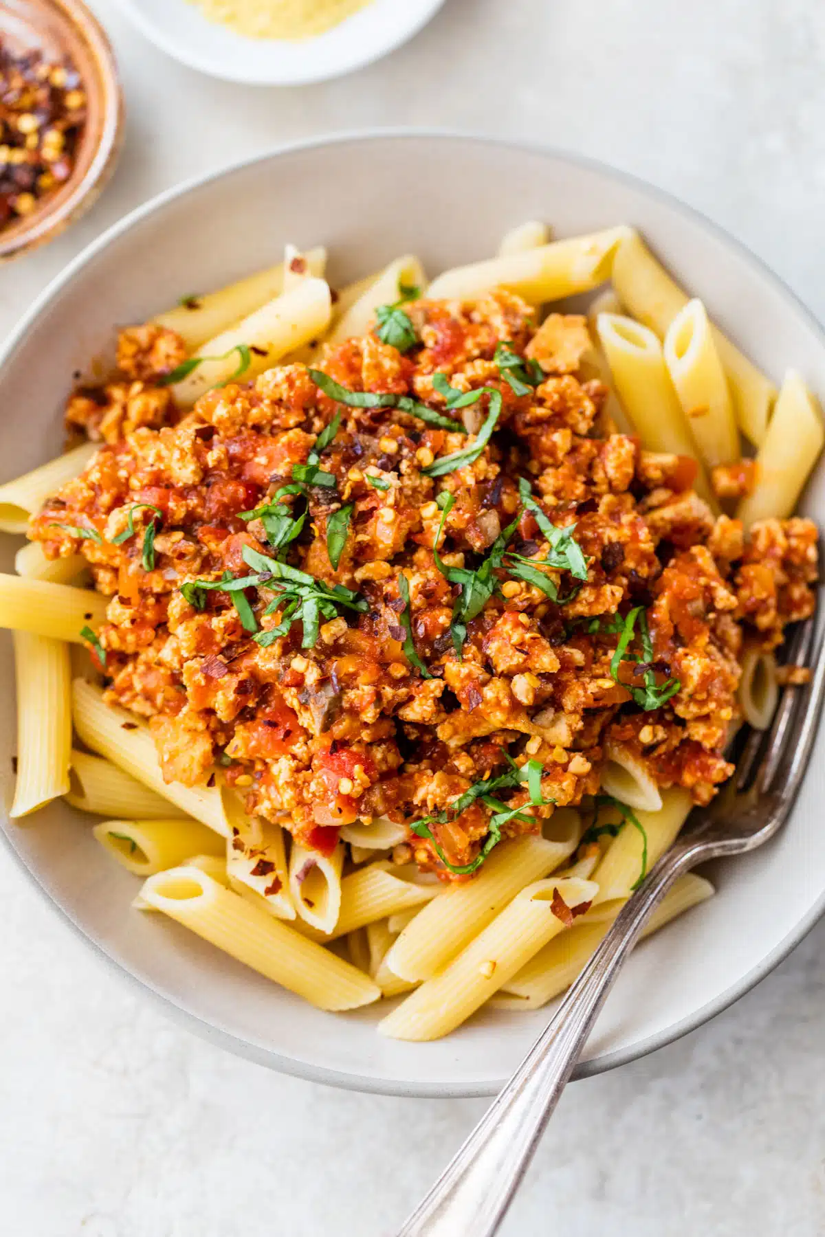a bowl of pasta topped with bolognese sauce and fresh basil
