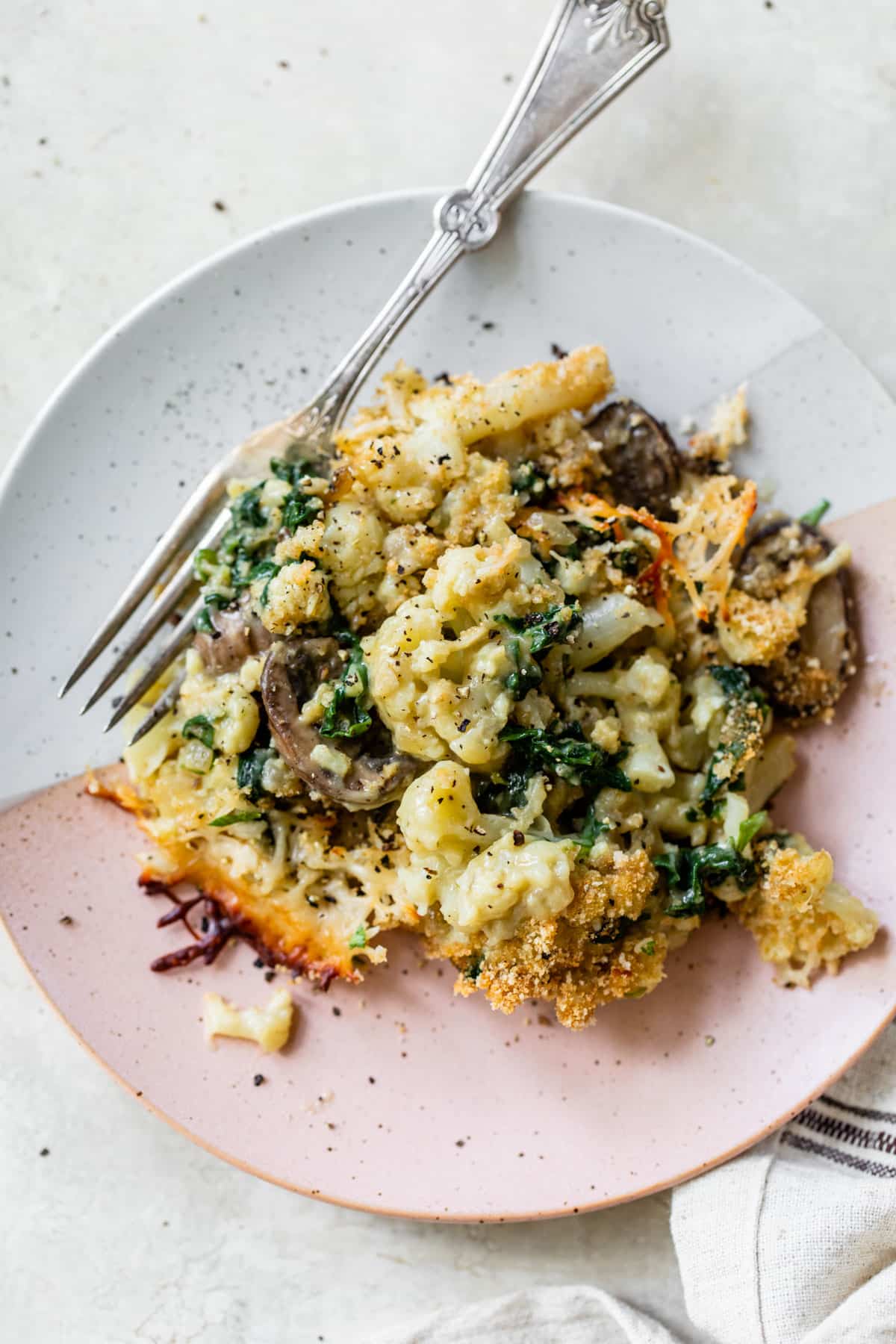 cooked cauliflower, mushrooms and spinach on a small plate with a fork