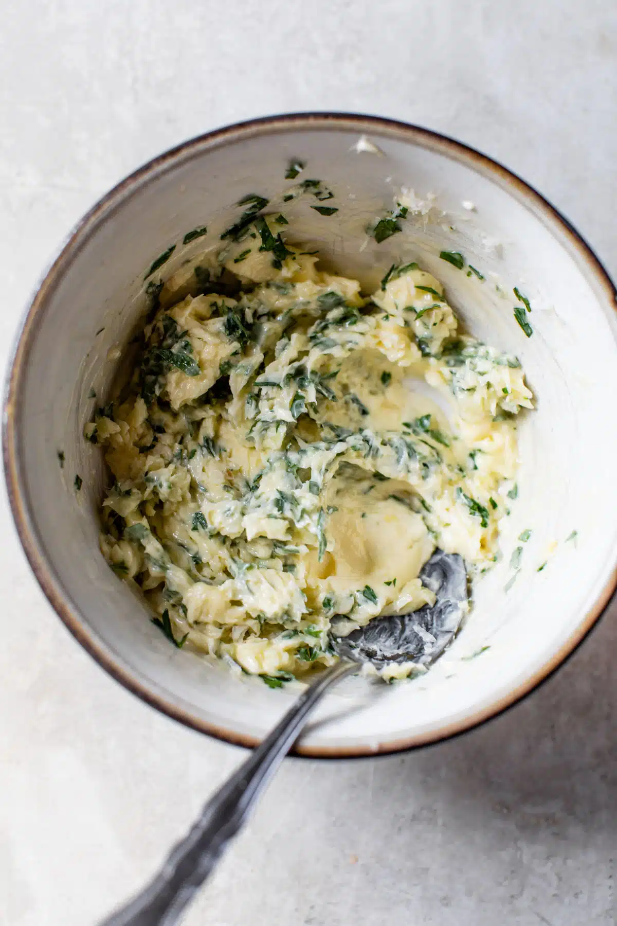 a bowl of garlic herb butter with a spoon