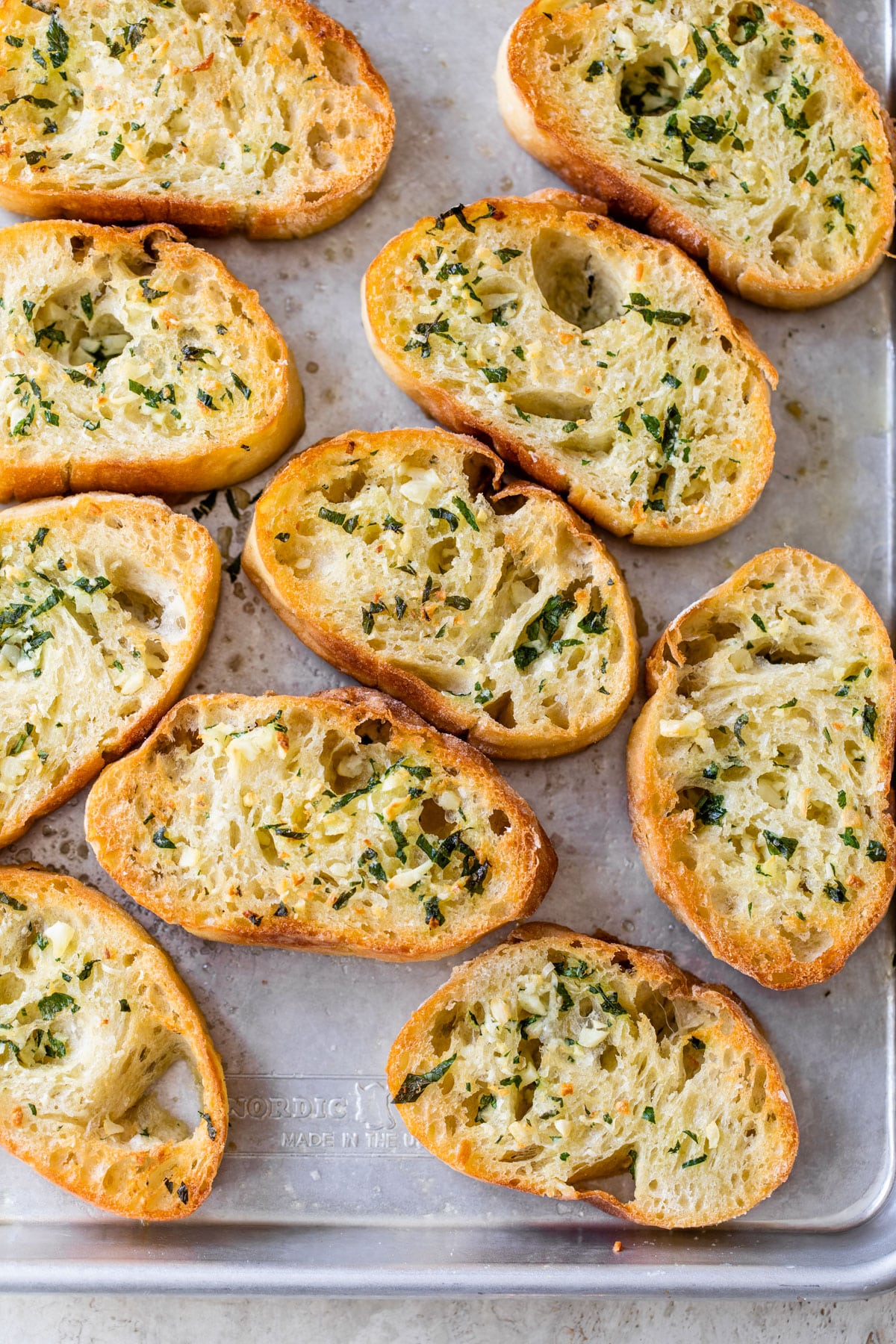 small bread slices on a baking sheet topped with garlic butter