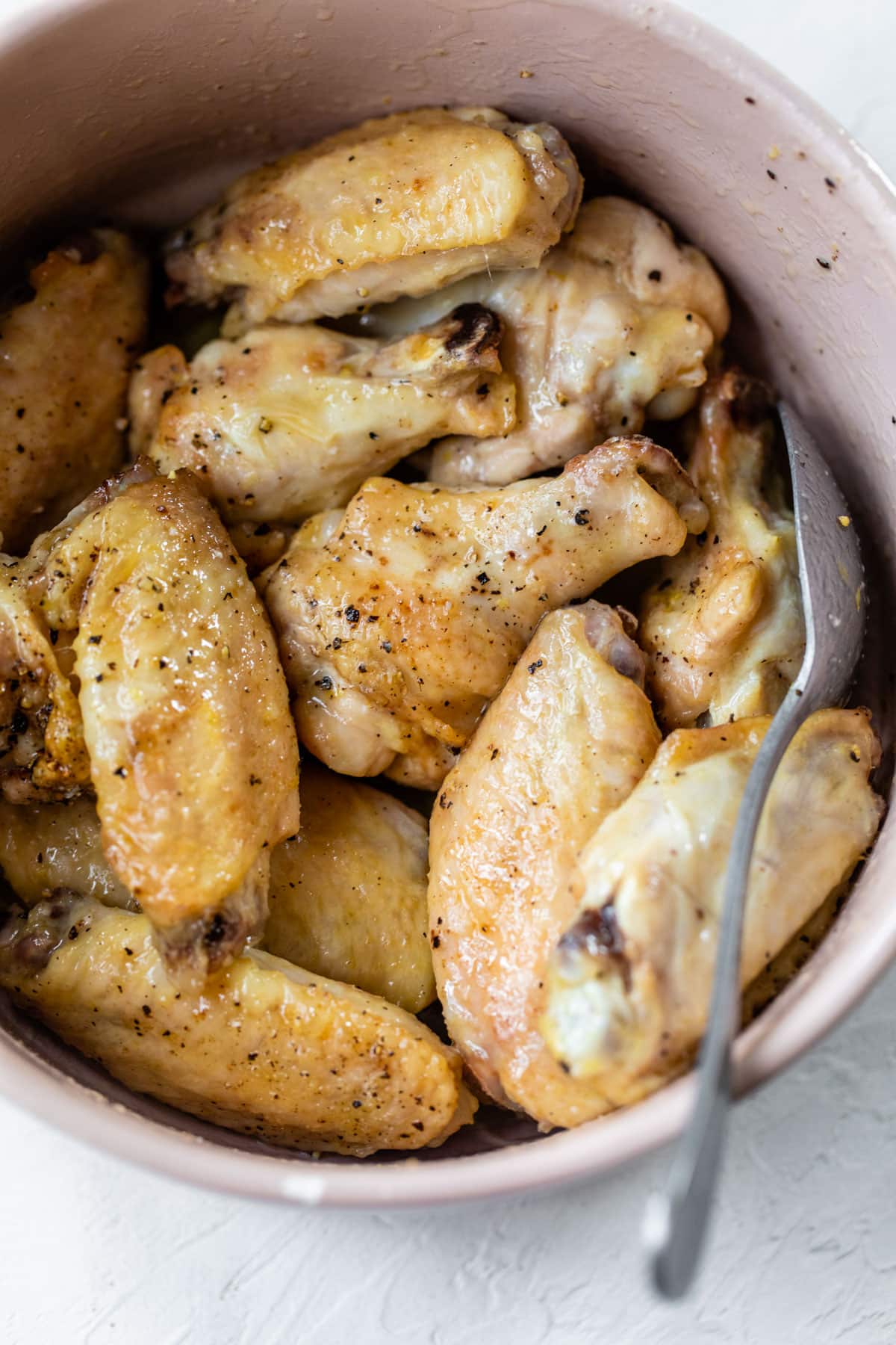 crispy chicken wings in a bowl mixed with butter and lemon juice
