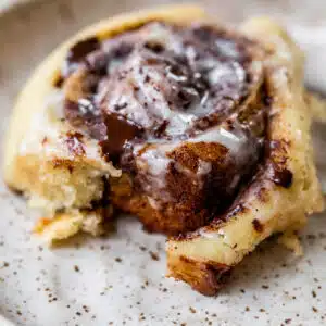 cinnamon roll on a plate topped with glaze and chocolate