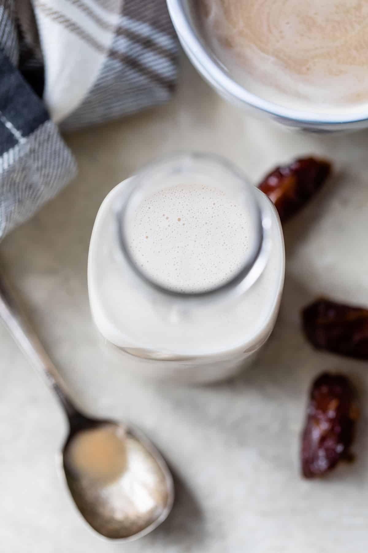 coffee creamer in a jar beside a mug of coffee and two dates