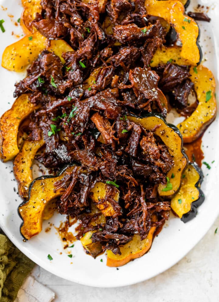a platter of roasted acorn squash topped with marinated pulled pork