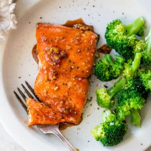 marinated salmon on a plate beside cooked broccoli