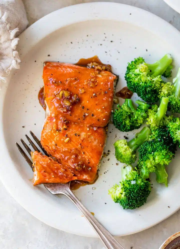 marinated salmon on a plate beside cooked broccoli
