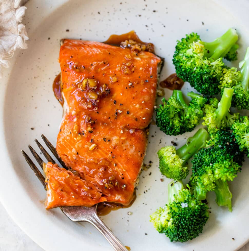 marinated salmon on a plate beside cooked broccoli