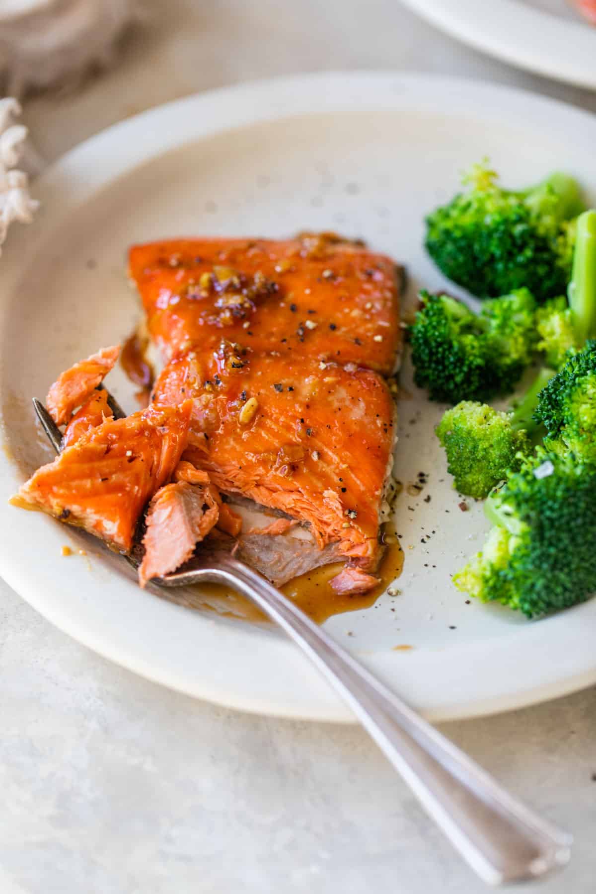 a marinated salmon fillet on a plate with broccoli and a fork