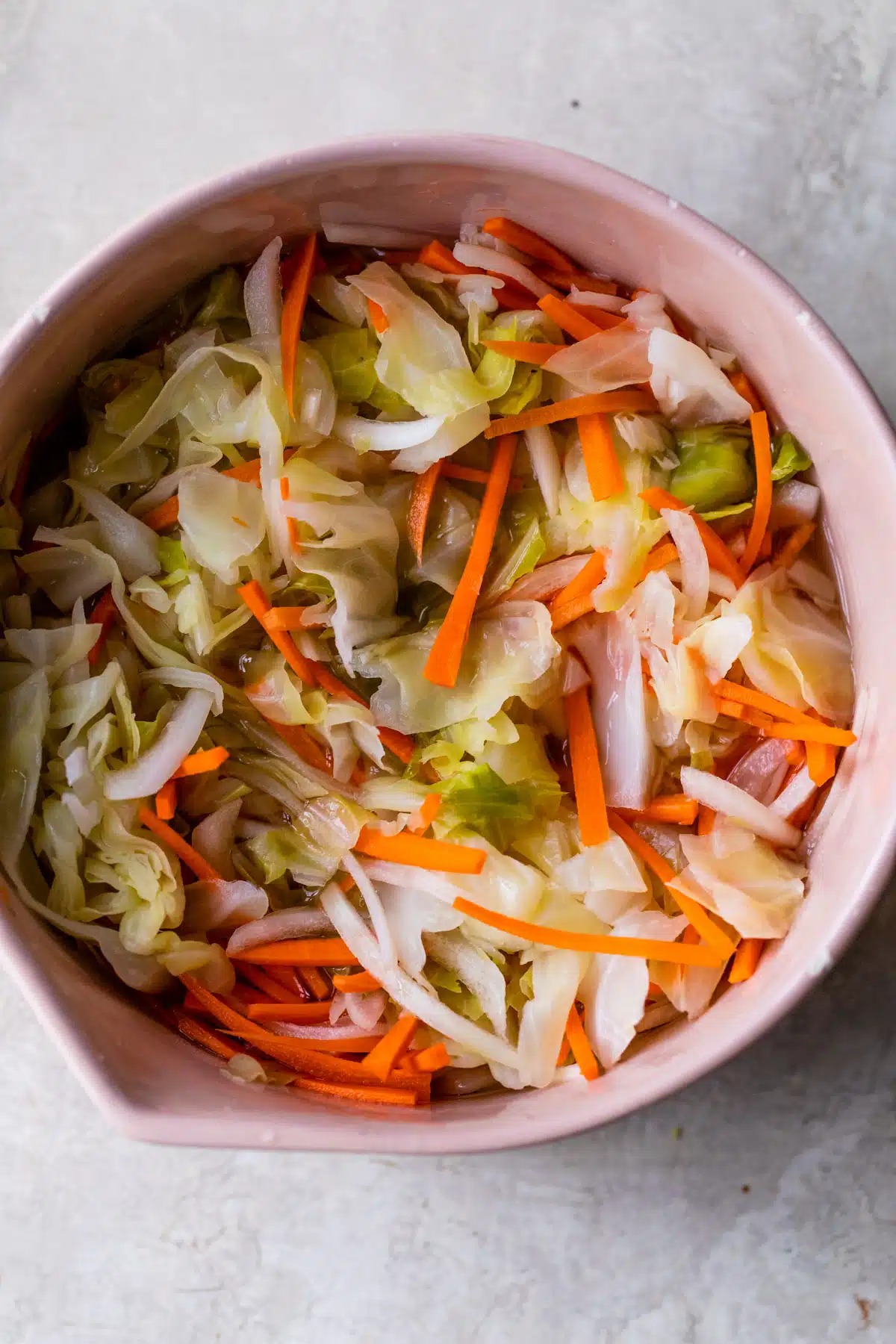a bowl filled with cabbage, carrots and sliced onion