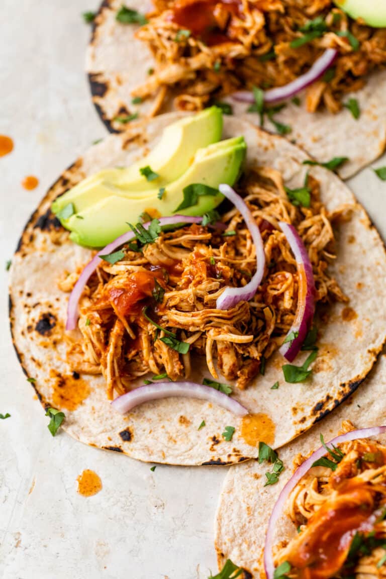 shredded chicken tacos with red onion and avocado
