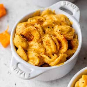 small dish filled with cheese-coated pasta beside a few cubes of butternut squash