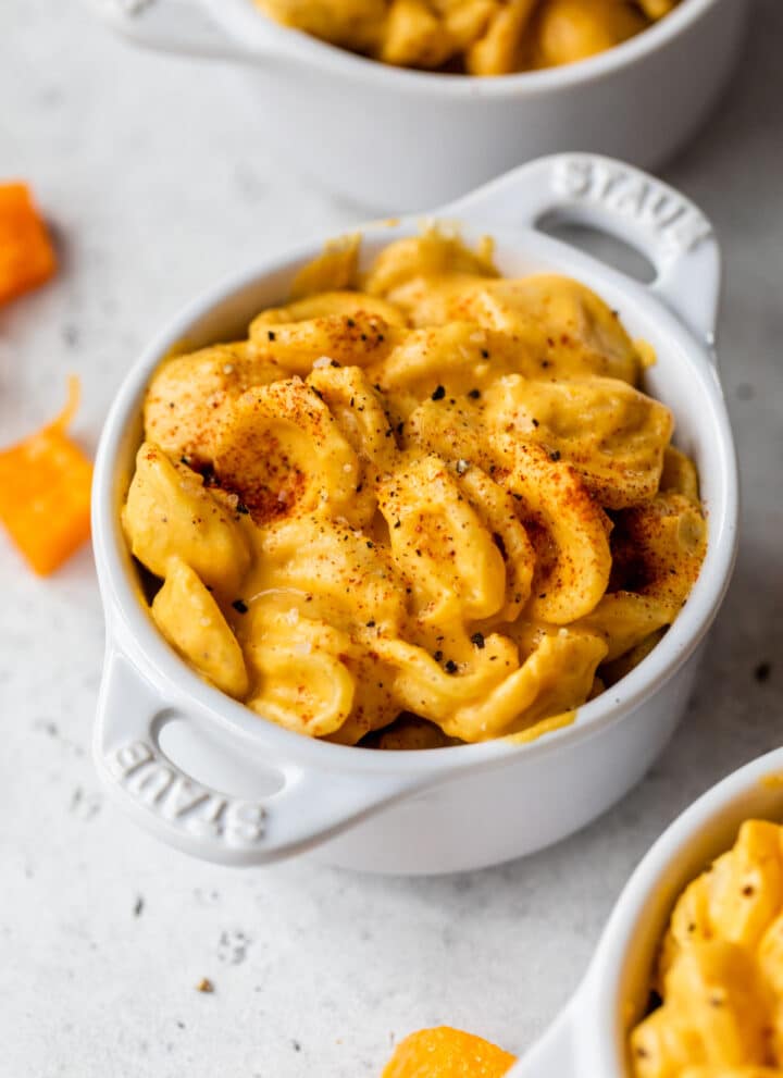 small dish filled with cheese-coated pasta beside a few cubes of butternut squash
