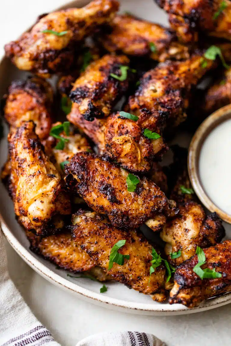 crispy chicken wings in a large bowl alongside a small bowl of ranch