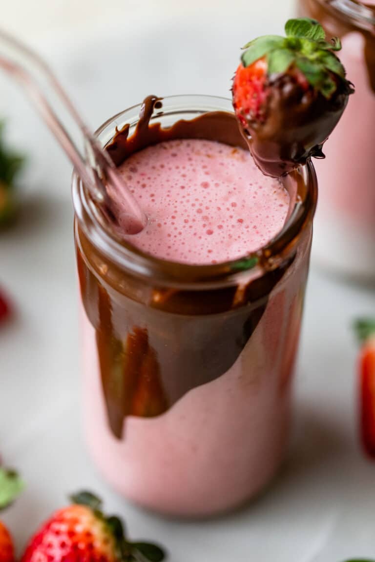 tall glass with chocolate on the inside of it filled with a strawberry smoothie