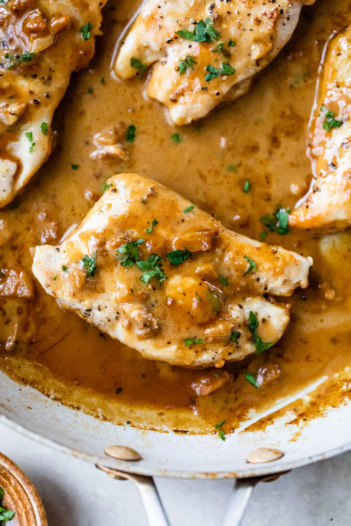 chicken breasts in a skillet with an orange and brown-colored sauce overtop