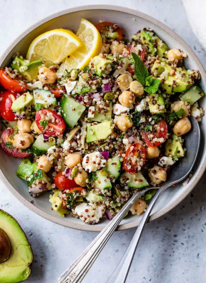 bowl with quinoa, feta cheese, cucumber, and other vegetables inside and with a spoon