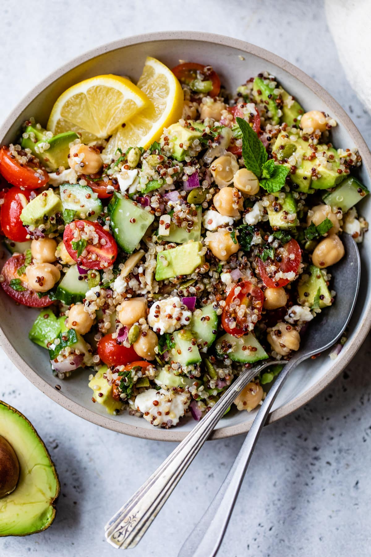 bowl with quinoa, feta cheese, cucumber, and other vegetables inside and with a spoon