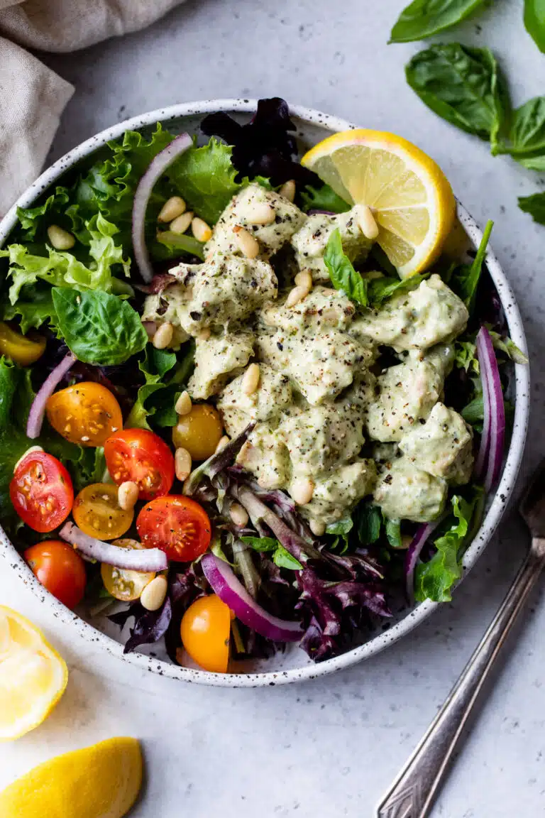 a salad with pieces of pesto covered chicken on top