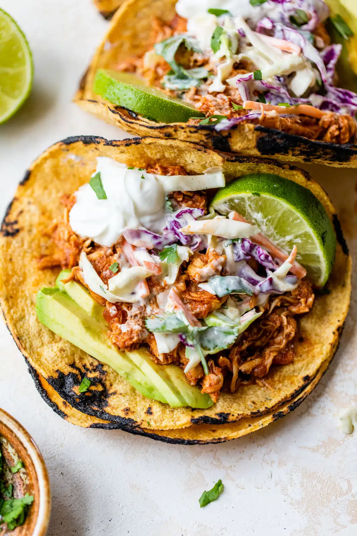 tacos with chicken, slaw, avocado, and a lime wedge