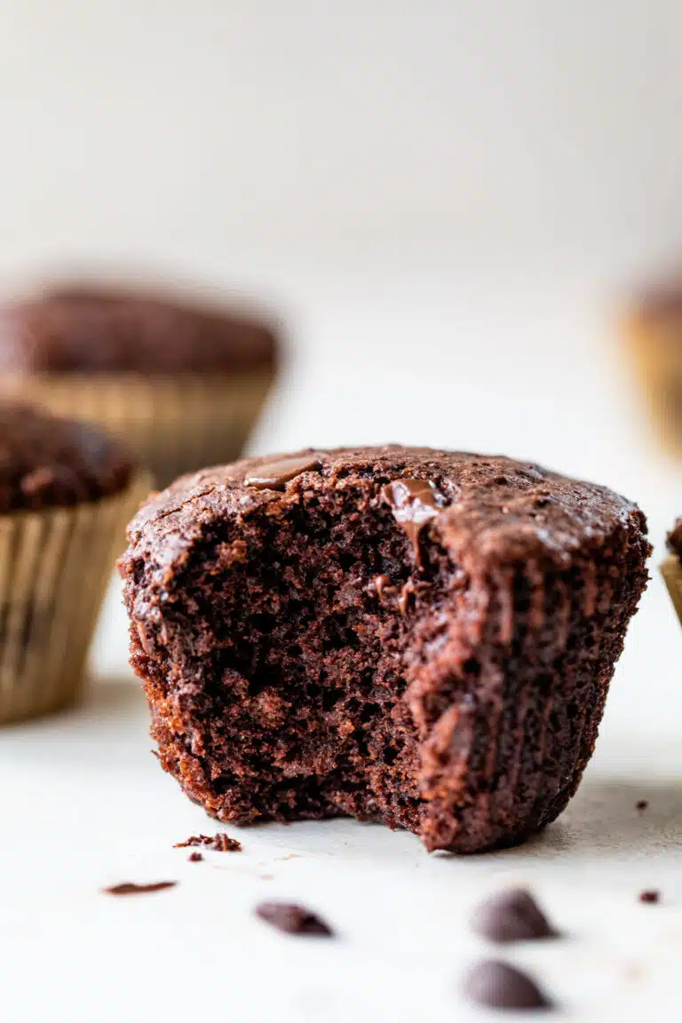 side view of a vegan chocolate muffin with a large bite on the side