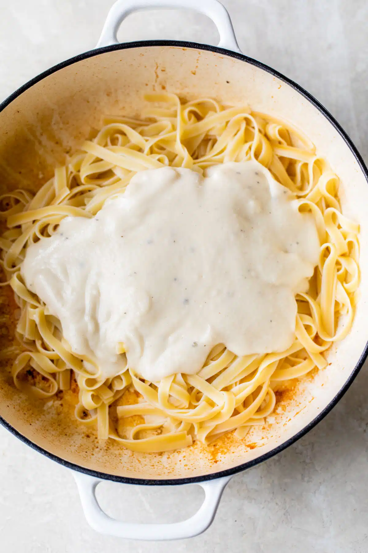 a dutch oven with fettuccine and alfredo sauce inside