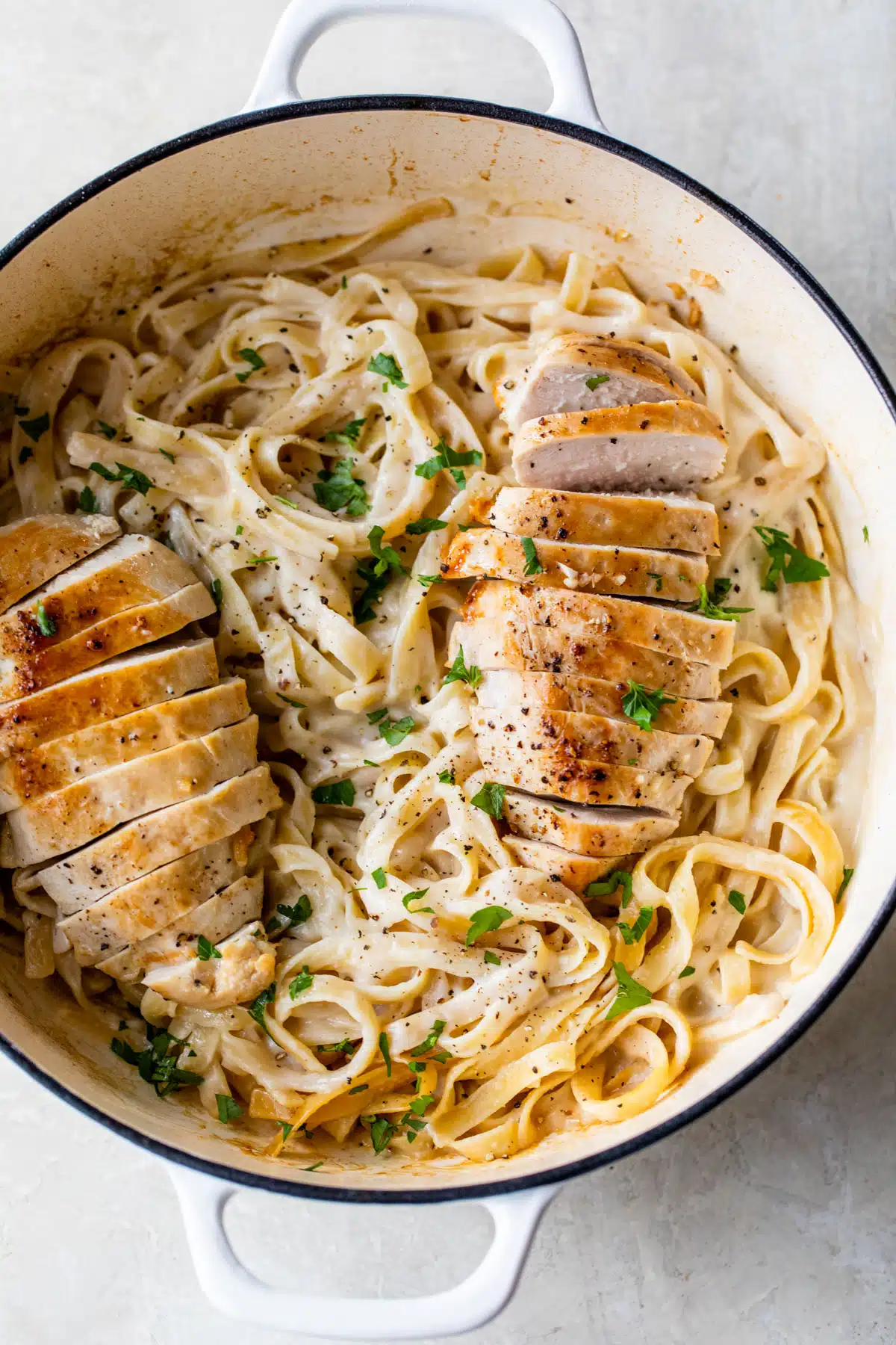 a dutch oven with fettuccine and chicken alfredo inside