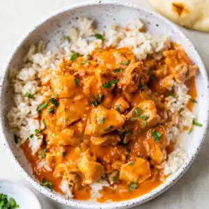a bowl of butter chicken overtop rice in a bowl
