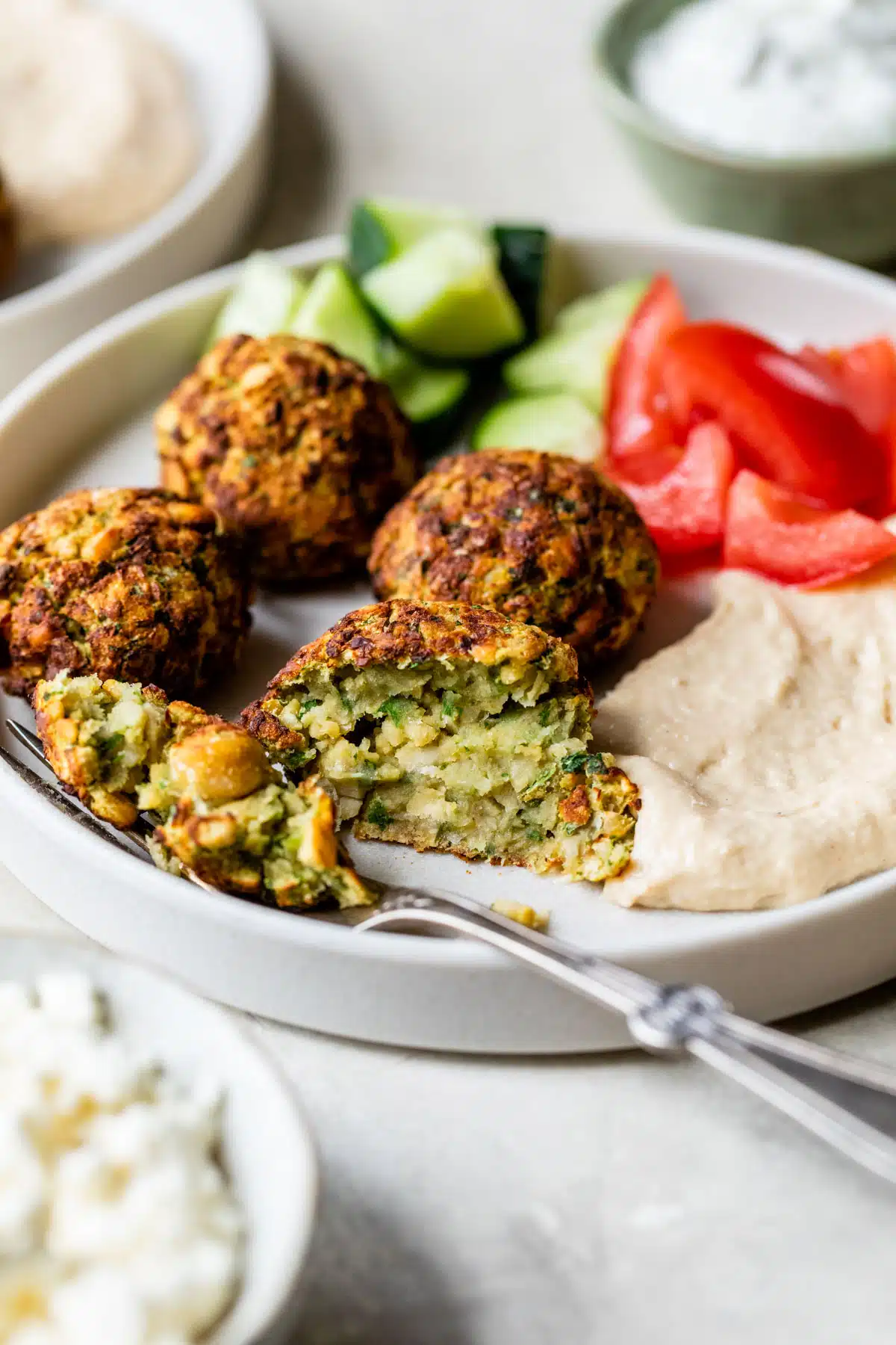 falafel on a plate with hummus, tomatoes and cucumber