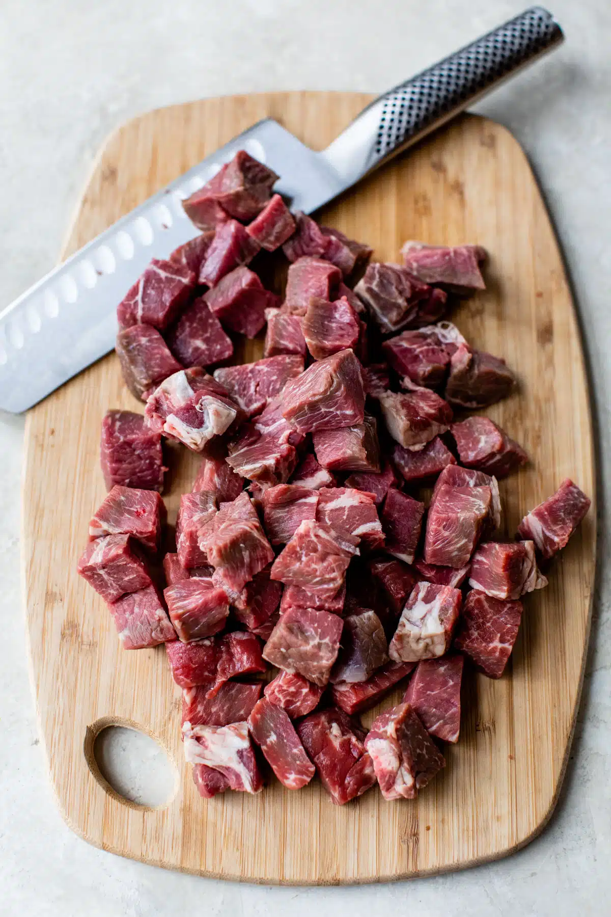 raw steak bites on a cutting board with a knife