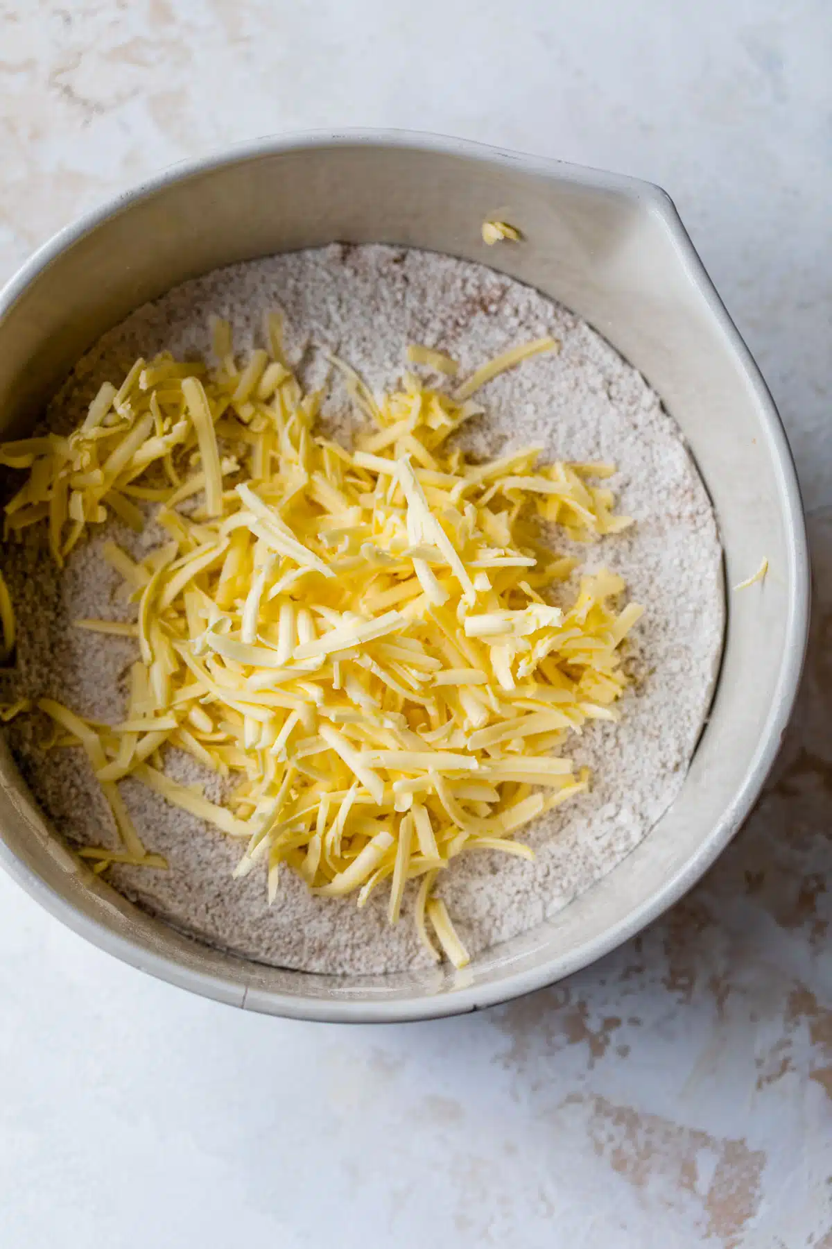 dry ingredients in a bowl with grated butter on top