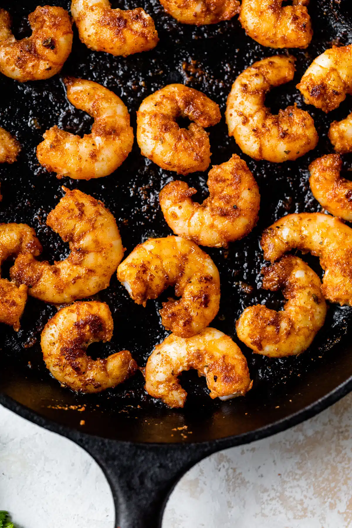 a close-up of shrimp cooking on a cast iron skillet
