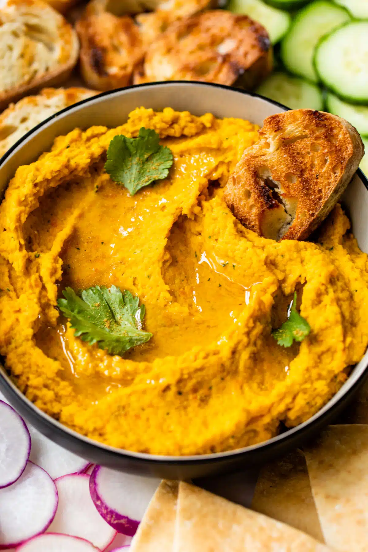 carrots hummus in a bowl with a slice of bread