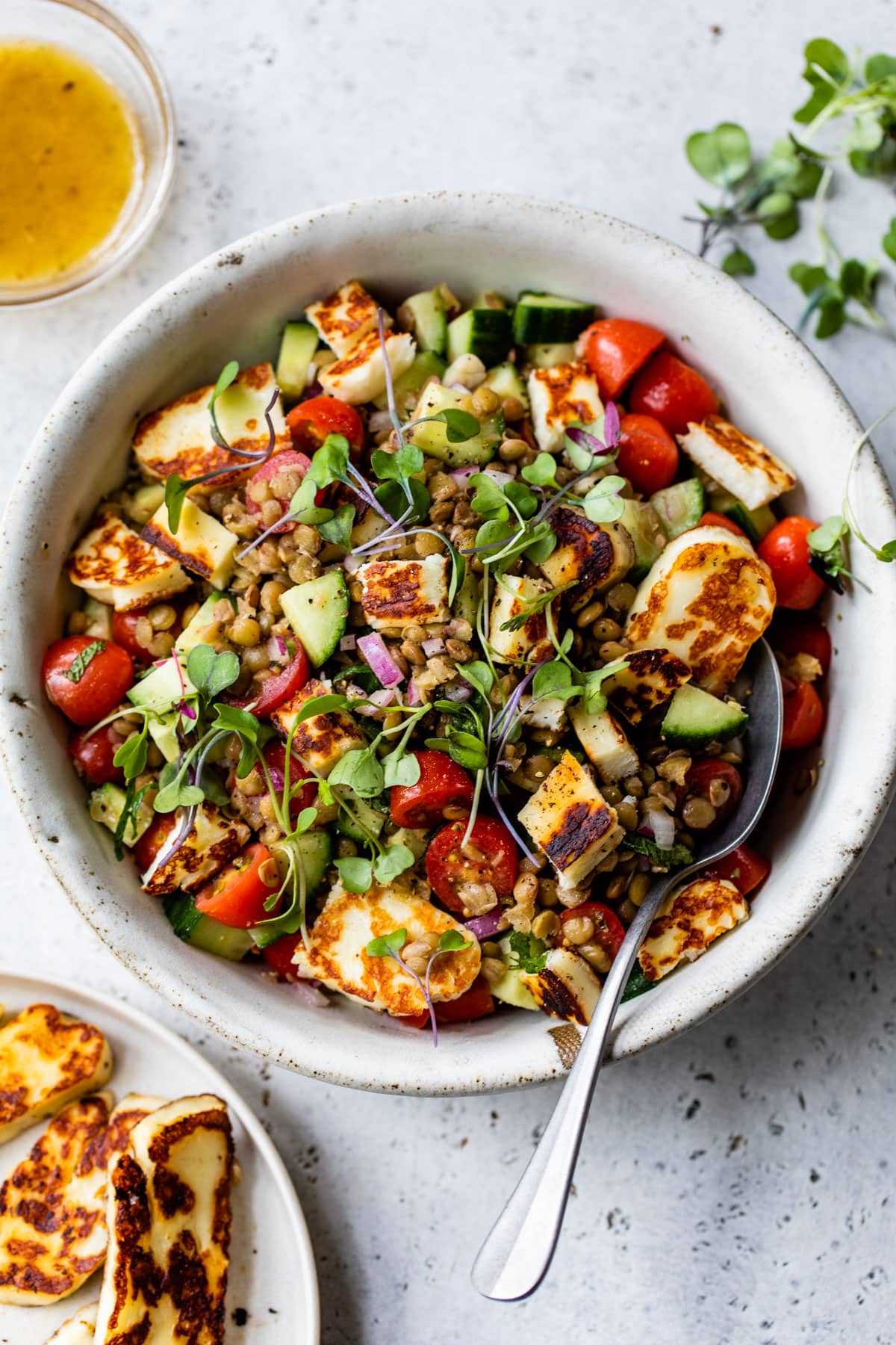 large bowl of lentils with tomatoes, cucumber and chopped cooked halloumi cheese