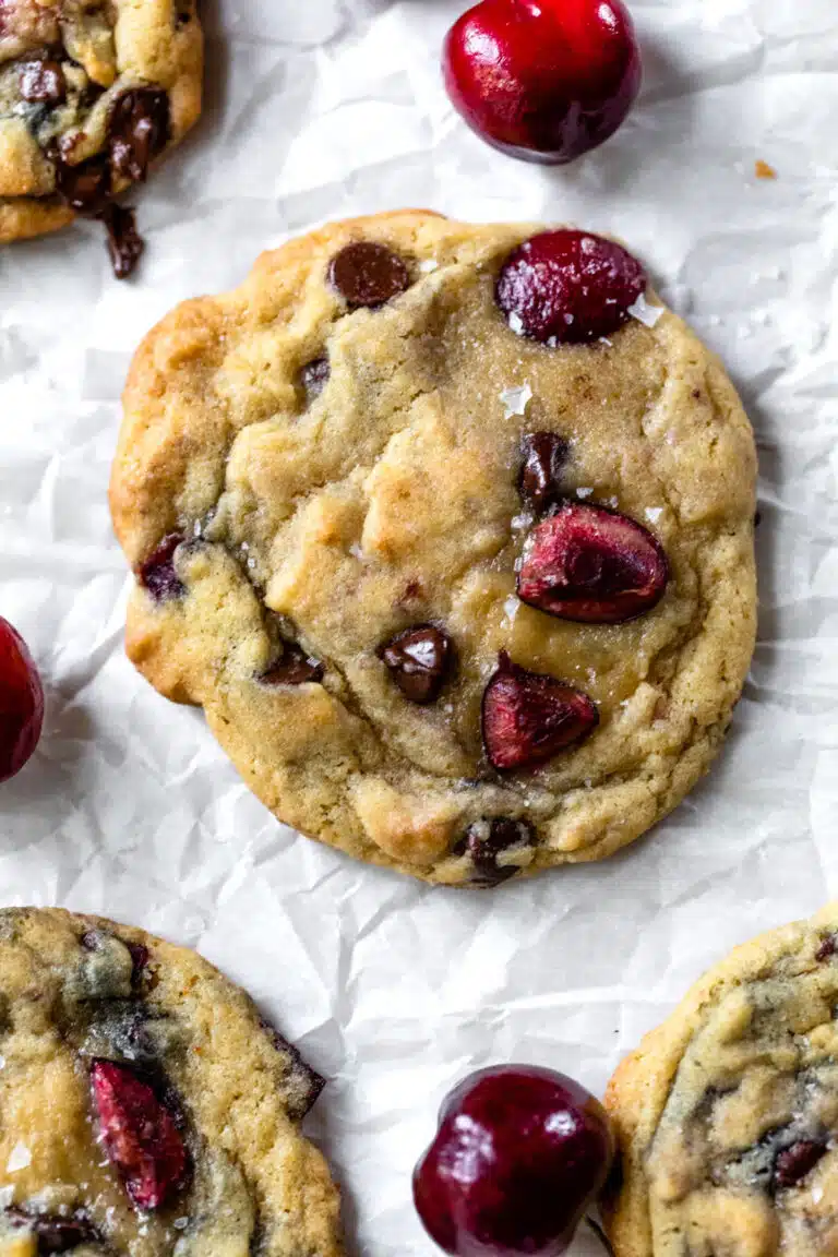 chocolate chip cookie with fresh cherries on a piece of parchment paper