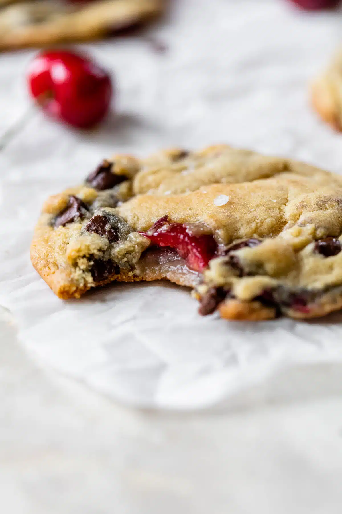 a chocolate chip cookie with cherries in it with a bite taken out of it