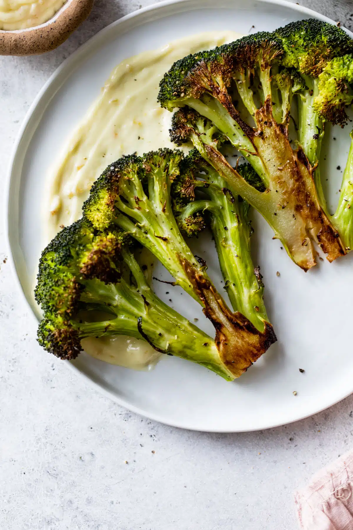 roasted broccoli crowns on a white plate with aioli