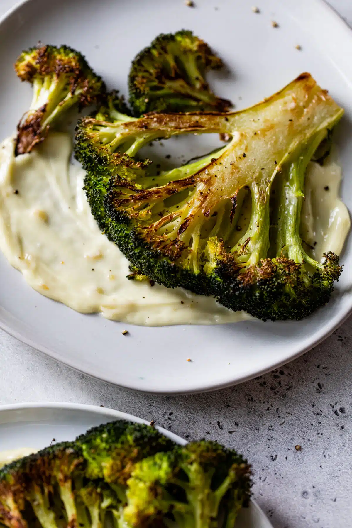 roasted broccoli crown on a plate with some aioli spread