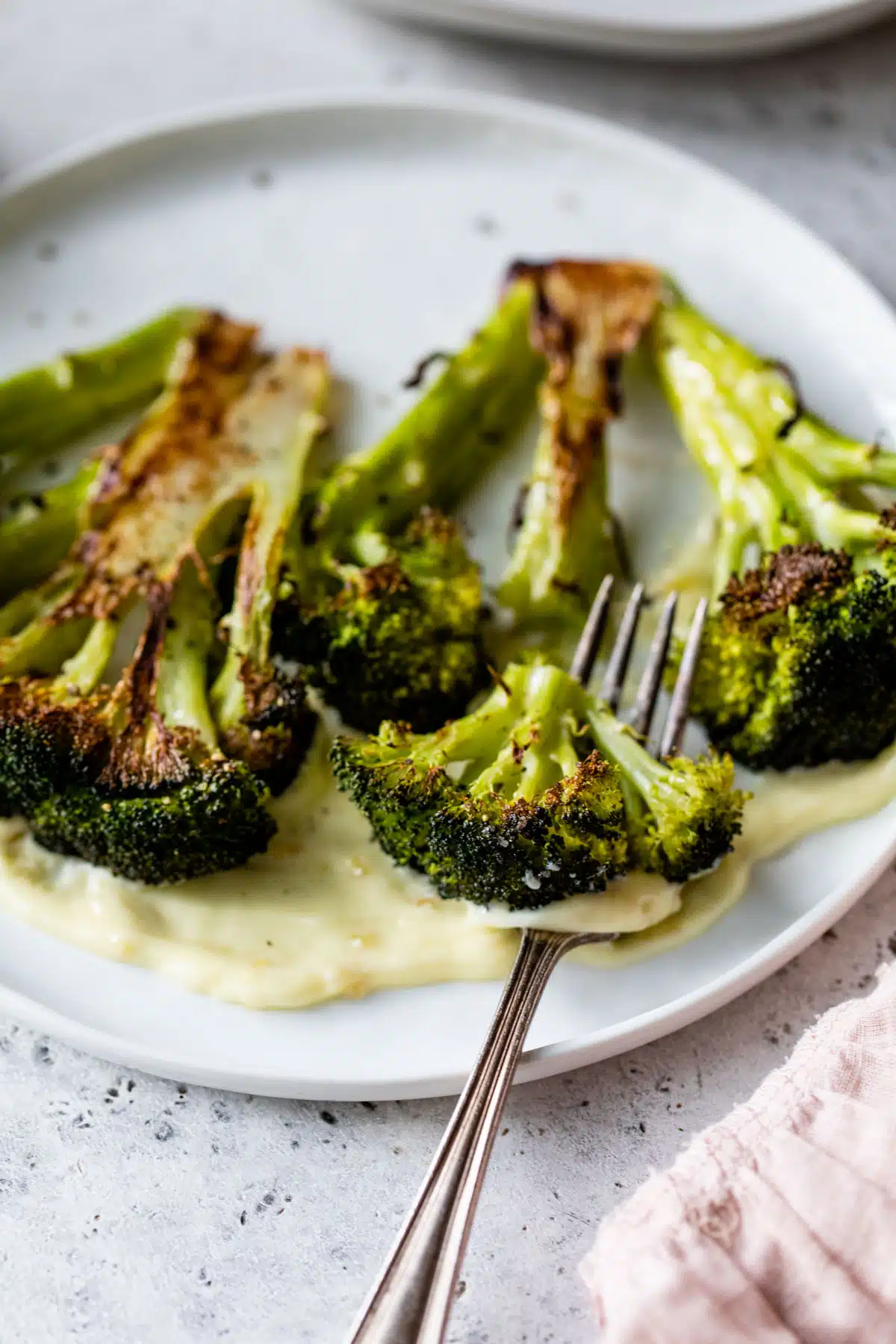 roasted broccoli on a plate being cut with a fork