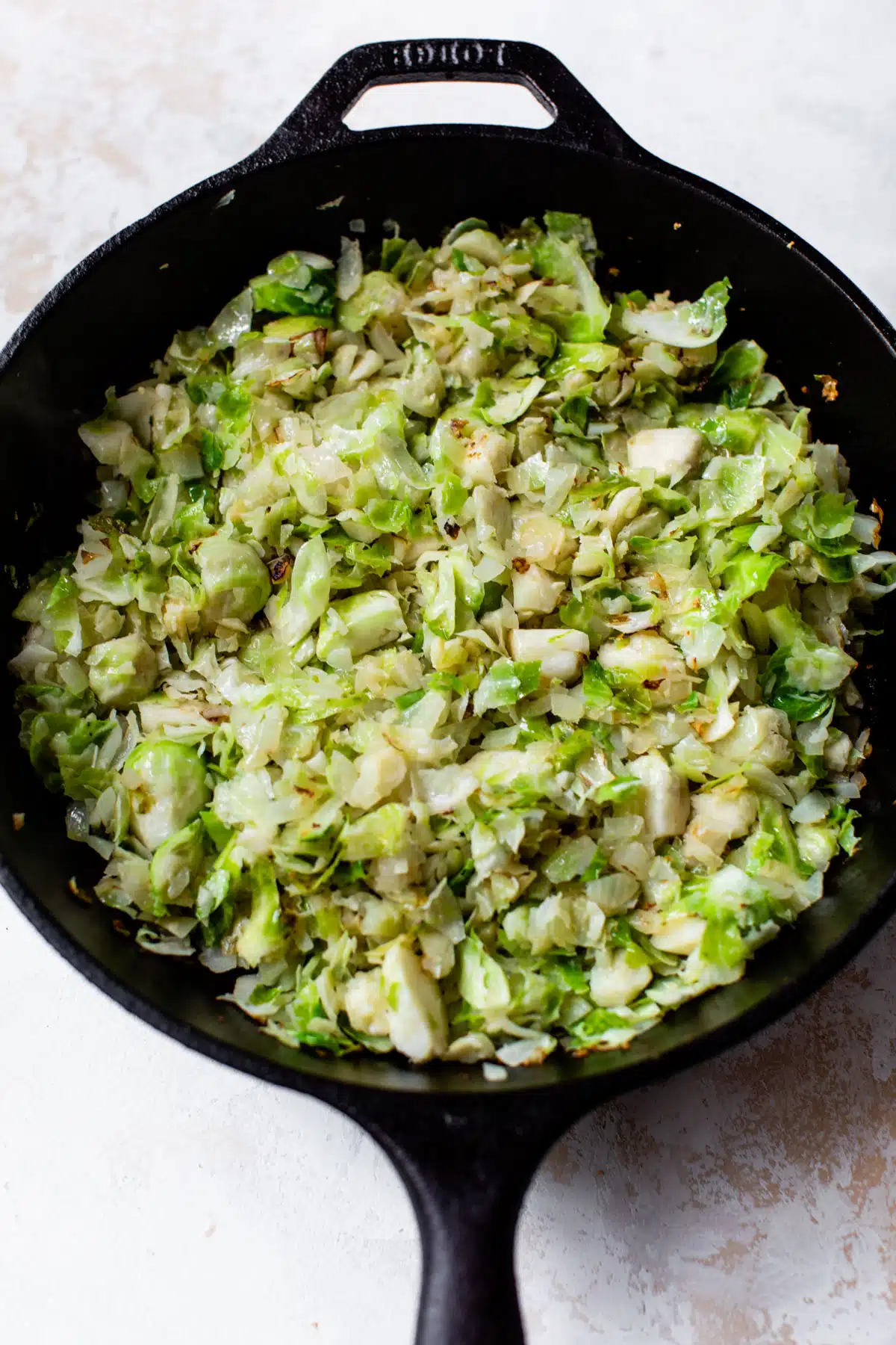 chopped brussels sprouts cooking in a cast iron skillet