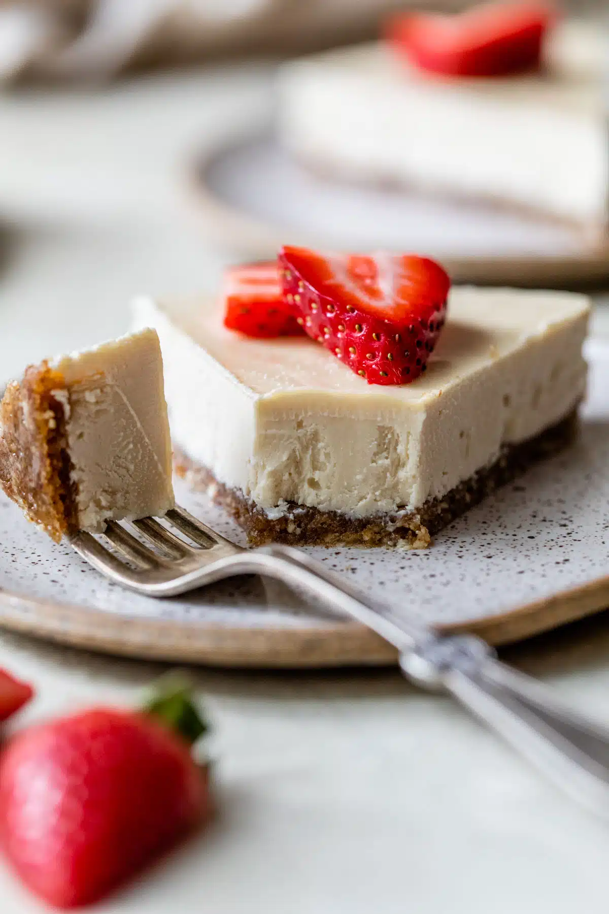 a side view of a slice of cheesecake on a plate with a fork