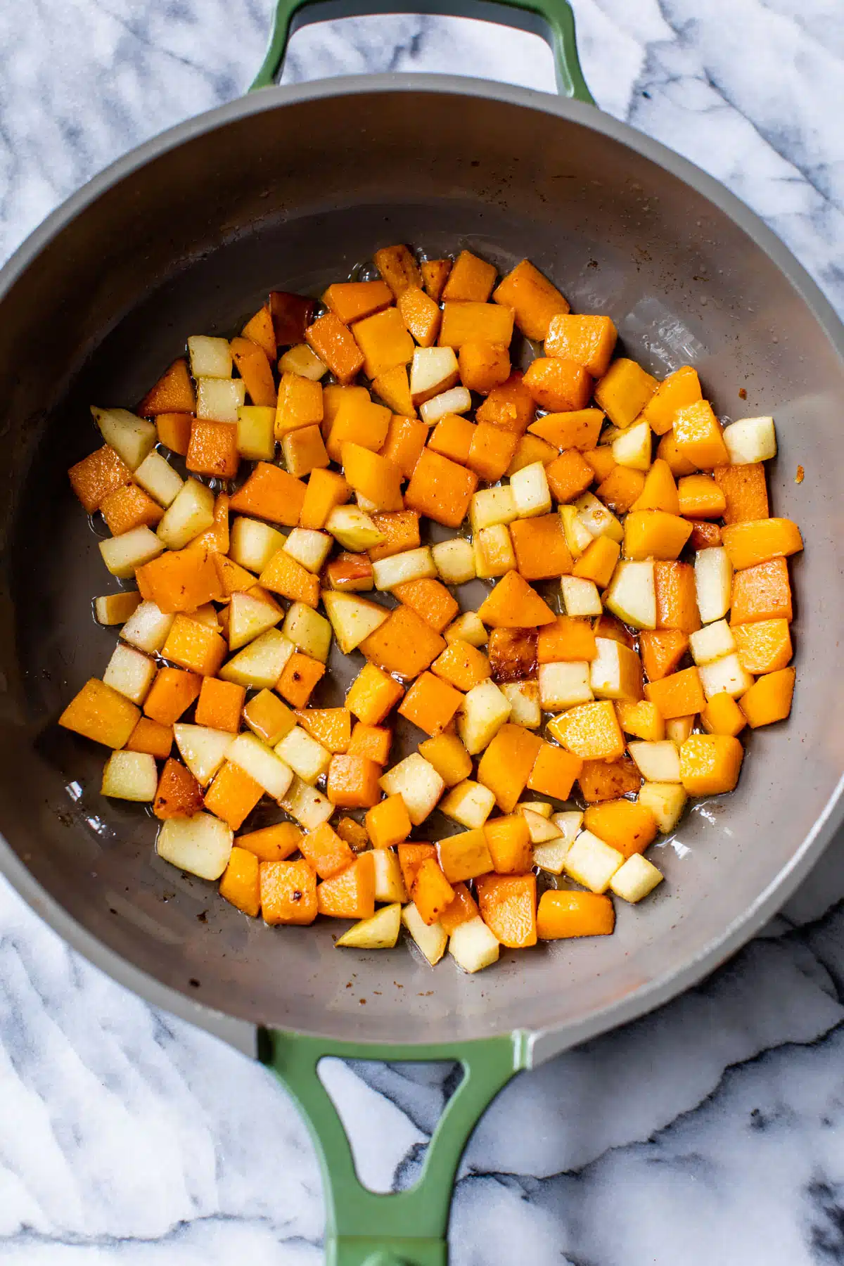 butternut squash pieces cooking in a skillet