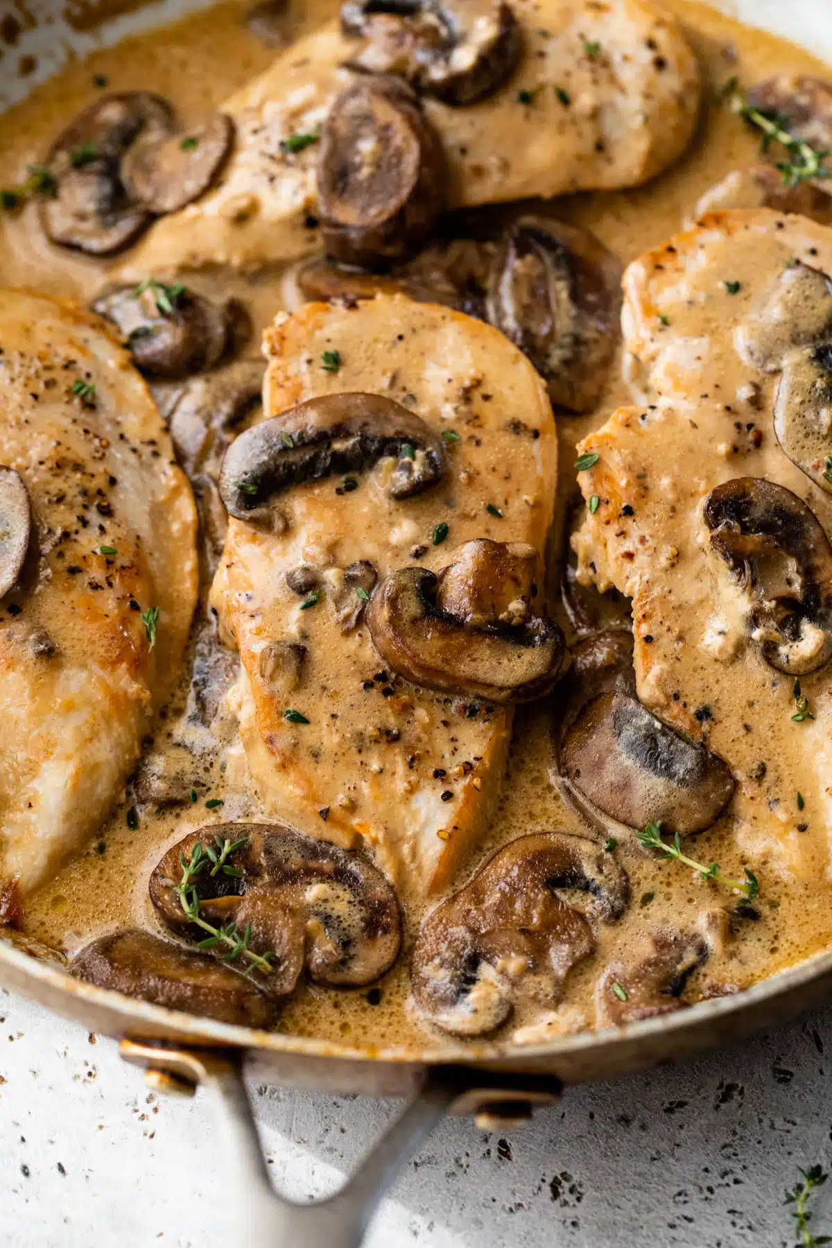 close up photo of cooked chicken breast in a skillet with a creamy mushroom sauce
