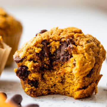 a side-view of a pumpkin chocolate chip muffin with a bite taken out