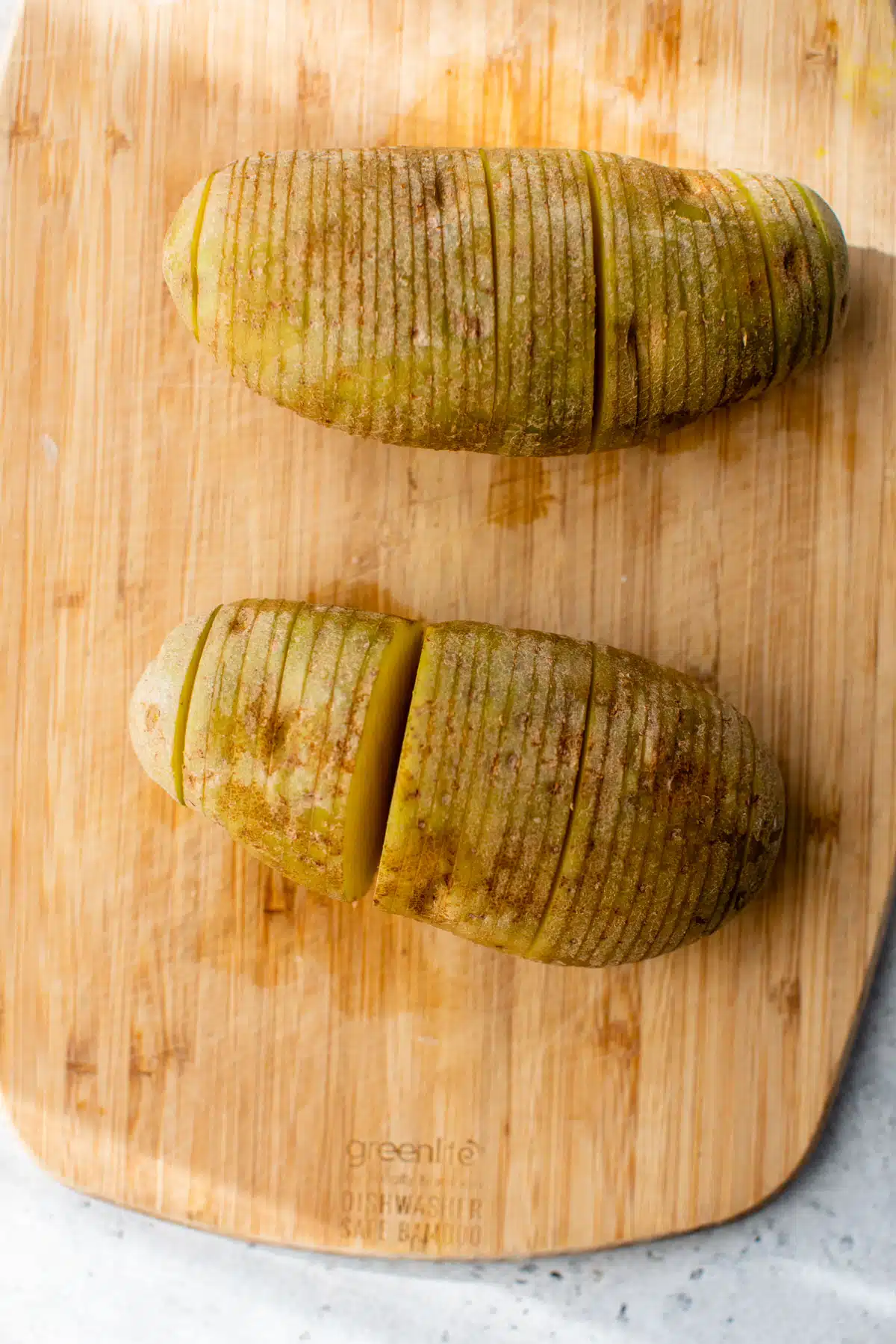 2 potatoes with slices though them on a cutting board