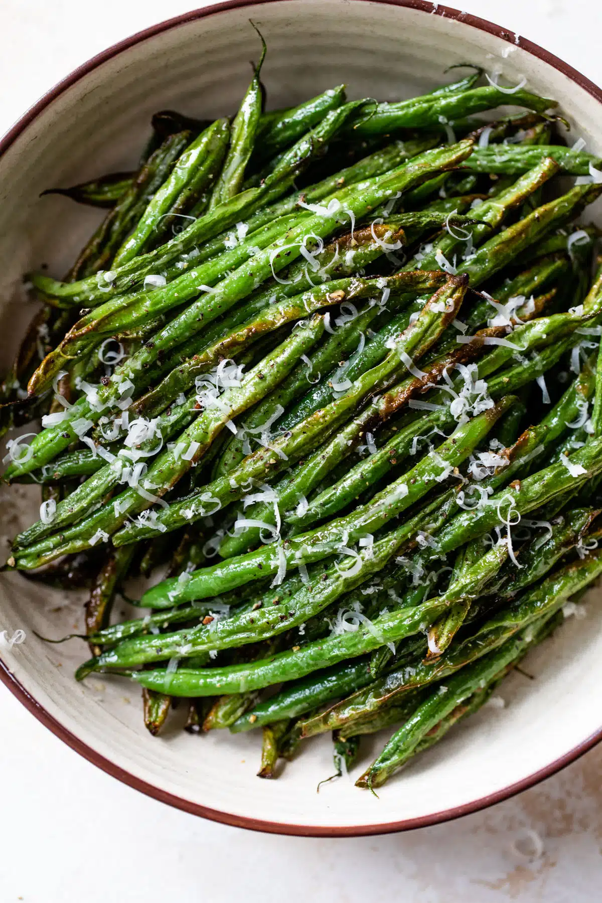 air fryer green beans in a bowl with grated cheese on top