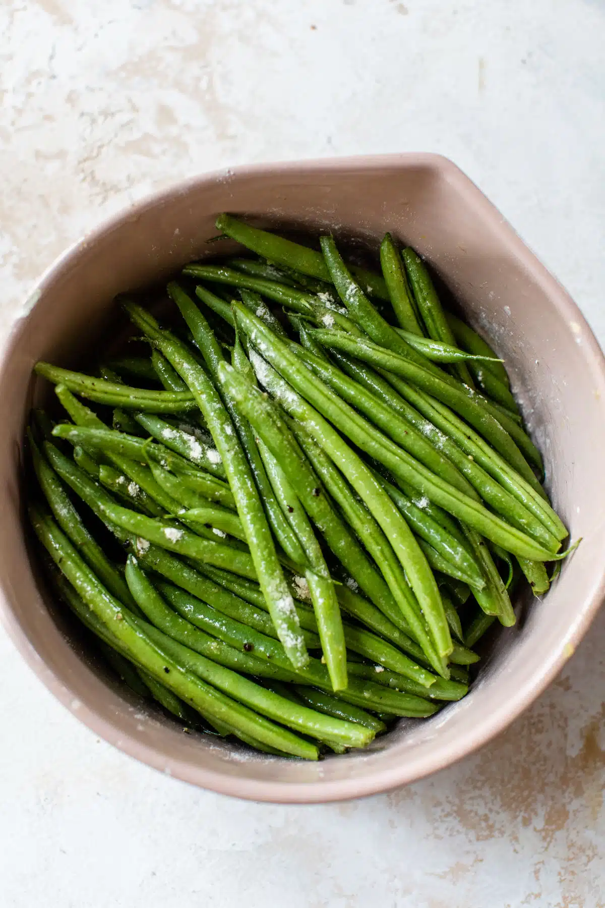 green beans in a bowl with salt and other spices on top
