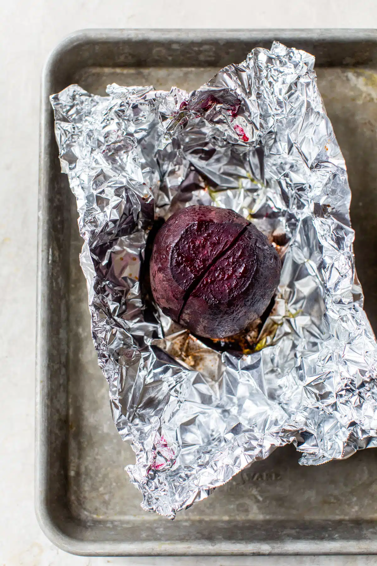 a roasted beet on aluminum foil on a baking sheet