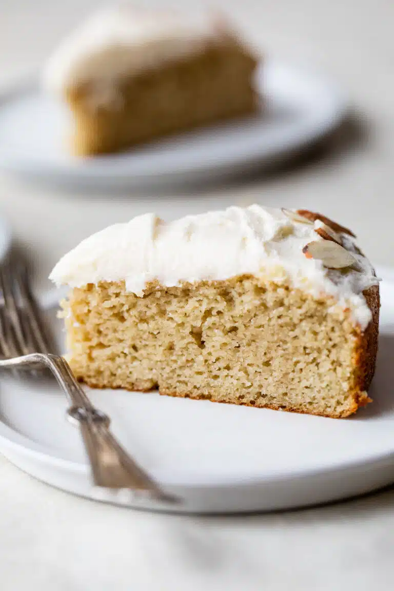 a side view slice of almond flour vanilla cake on a plate with a fork