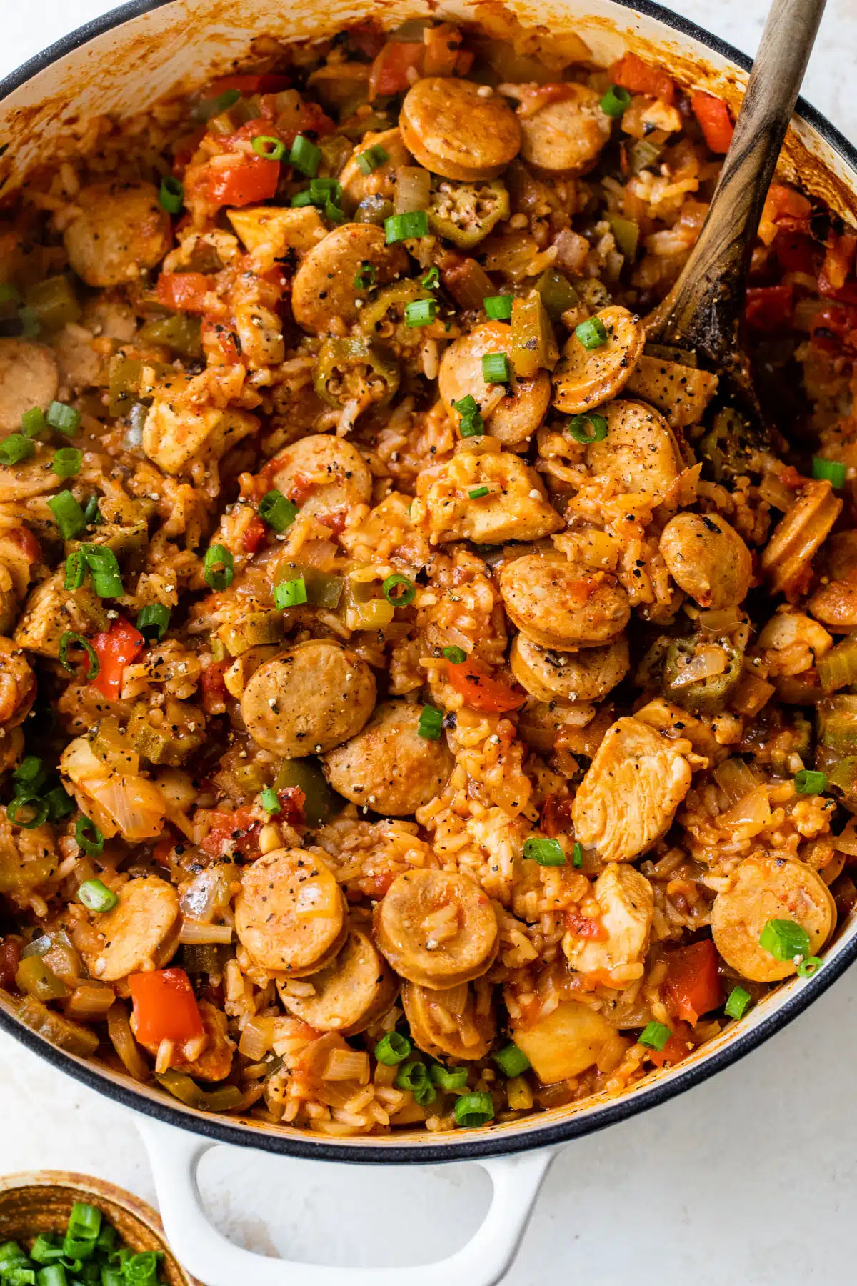 overview of chicken and sausage jambalaya in a dutch oven with a wooden spoon