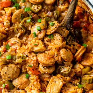 close-up of chicken and sausage jambalaya in a dutch oven with a wooden spoon